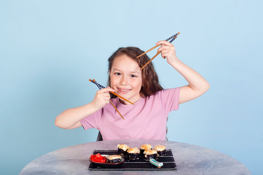 A girl skillfully playing a tune on a set of chopsticks, showcasing her dexterity and musical talent.